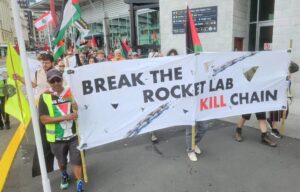 “Break the Rocket Lab kill chain,” says the protester banner on Queens Wharf
